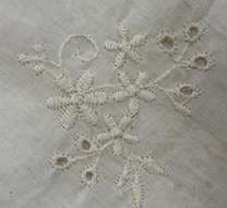 Close-up of raised white floral embroidery with eyelets.
