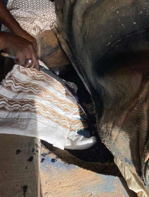 Resisted fabric being peeled back from a dark dye bath.