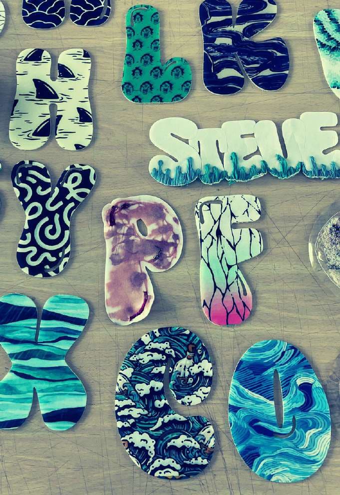 Cut fabric letters in printed patterns laid out on a table.