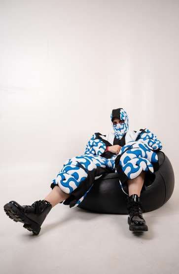 The squiggle suit worn seated on a black beanbag.