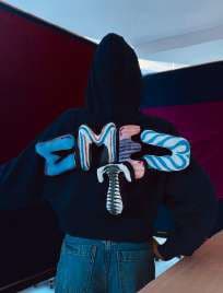 The back of a black hoodie with puffed, printed letters.