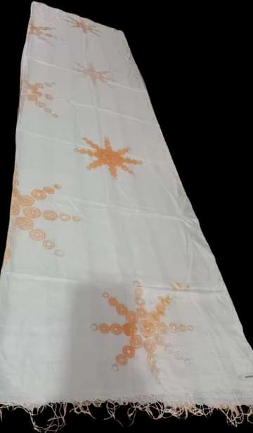 White cloth with orange stitch-resist outlines of stars before dyeing.