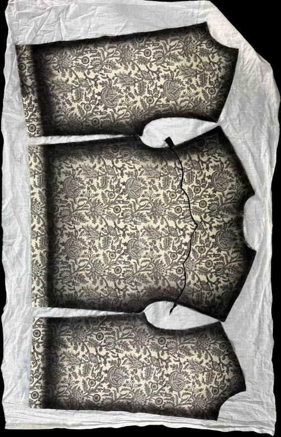 Jacket pattern pieces block-printed in a dense floral repeat, laid on raw fabric.
