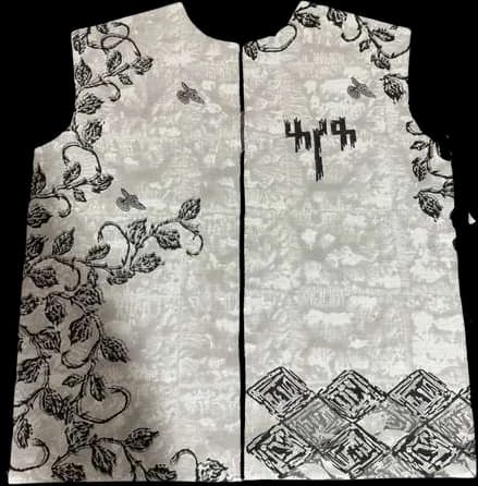 A block-printed vest panel with floral prints, a lettered motif, and a stepped border.