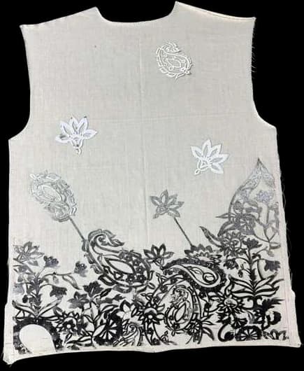 A pale vest with layered black block prints and white flowers along the hem.